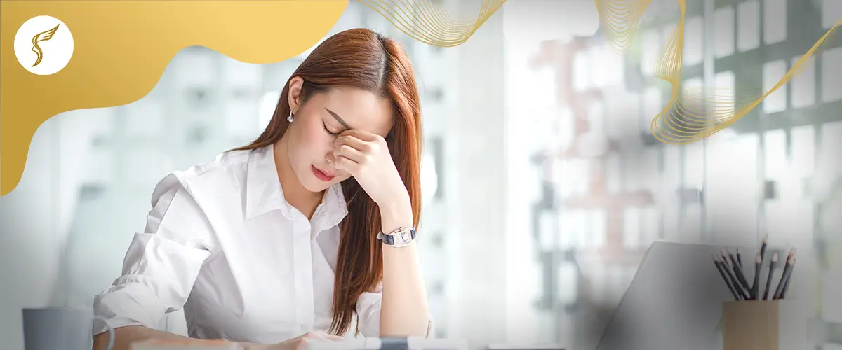 Woman experiencing eye strain and headache while working on a laptop, showing symptoms of digital eye strain and vision fatigue.