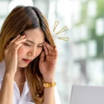 Woman experiencing eye strain and headache while using a laptop, a common symptom of uncorrected vision problems like astigmatism