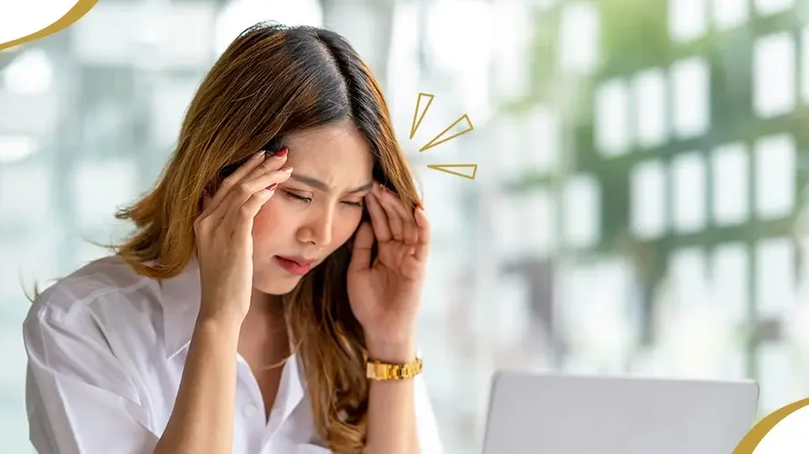 Woman experiencing eye strain and headache while using a laptop, a common symptom of uncorrected vision problems like astigmatism