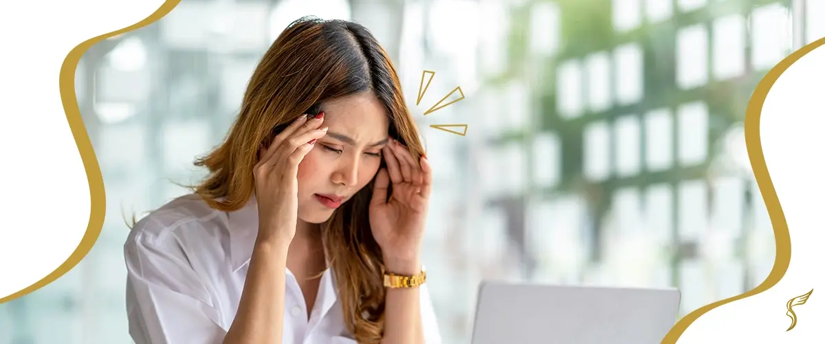 Woman experiencing eye strain and headache while using a laptop, a common symptom of uncorrected vision problems like astigmatism