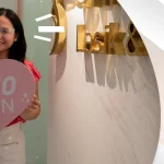 Happy woman holding a heart-shaped sign that says ‘20/10 Vision’ after LASIK surgery at Shinagawa Lasik & Aesthetics Center