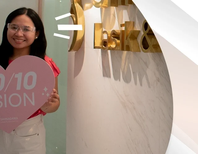 Happy woman holding a heart-shaped sign that says ‘20/10 Vision’ after LASIK surgery at Shinagawa Lasik & Aesthetics Center