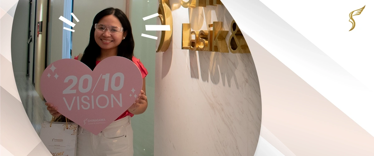 Happy woman holding a heart-shaped sign that says ‘20/10 Vision’ after LASIK surgery at Shinagawa Lasik & Aesthetics Center