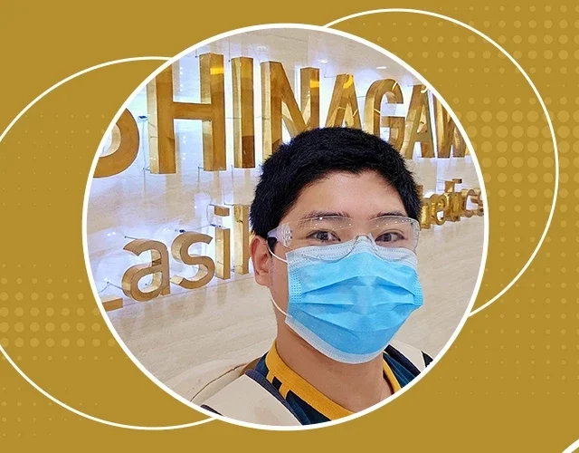 Smiling man wearing a face mask and goggles inside Shinagawa Lasik & Aesthetics Center, standing in front of the clinic’s gold signage