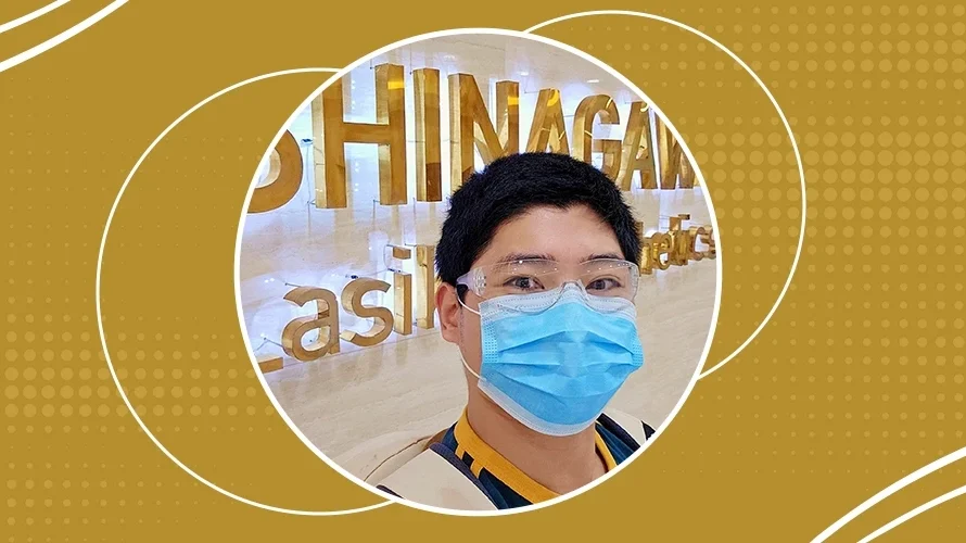 Smiling man wearing a face mask and goggles inside Shinagawa Lasik & Aesthetics Center, standing in front of the clinic’s gold signage