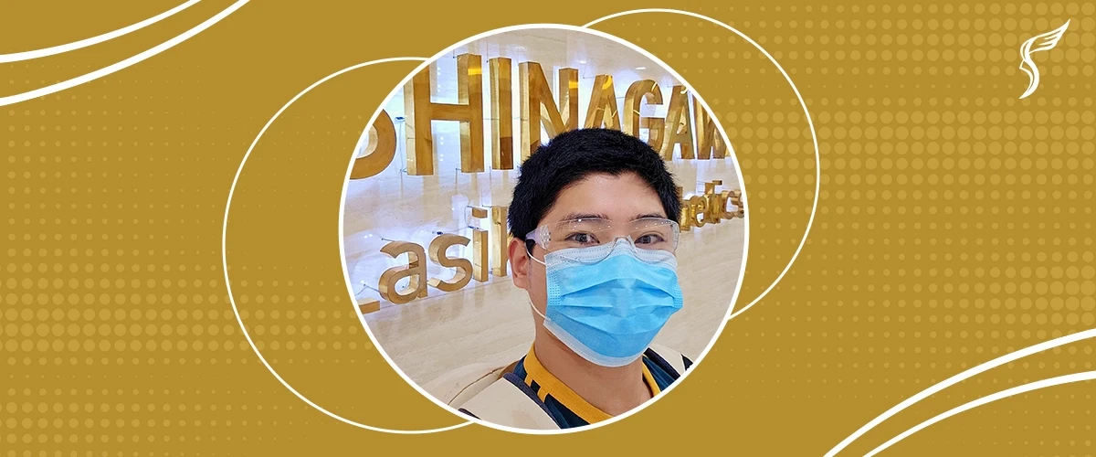 Smiling man wearing a face mask and goggles inside Shinagawa Lasik & Aesthetics Center, standing in front of the clinic’s gold signage