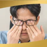 Man rubbing his eyes while wearing glasses, showing signs of eye strain or irritation that may affect vision health