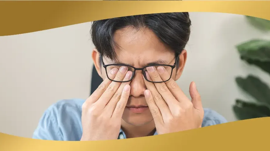 Man rubbing his eyes while wearing glasses, showing signs of eye strain or irritation that may affect vision health
