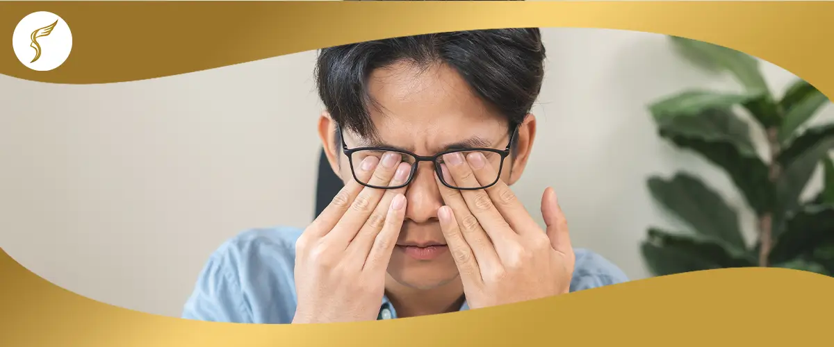 Man rubbing his eyes while wearing glasses, showing signs of eye strain or irritation that may affect vision health