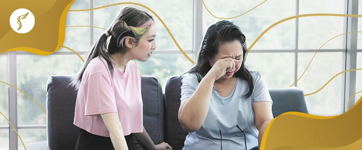 Elderly woman rubbing her eyes in discomfort while sitting on a couch, comforted by a younger woman, symbolizing eye health issues and family support