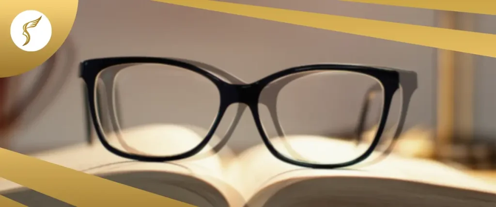 Black eyeglasses resting on an open book, symbolizing reading clarity and vision correction, with gold branding design.
