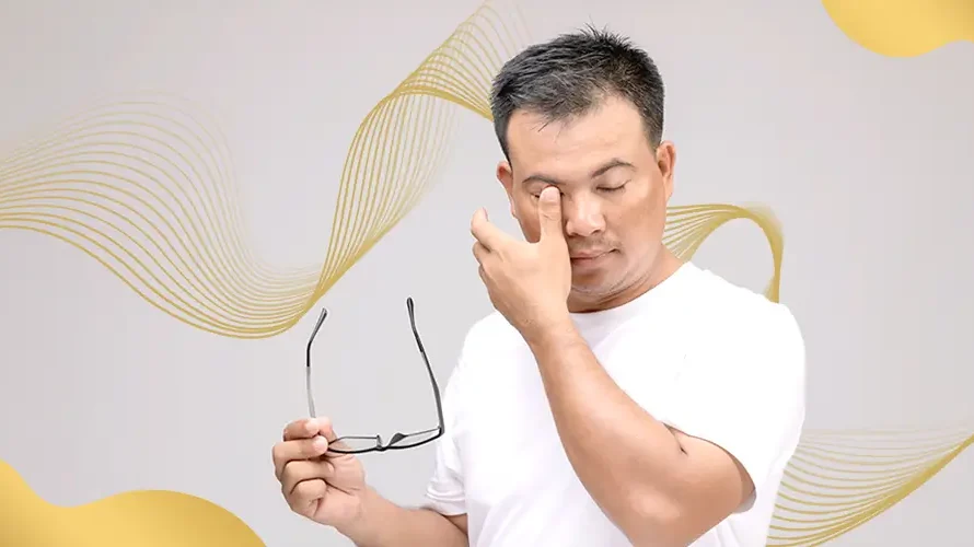 Man rubbing his eyes while holding eyeglasses, showing discomfort or signs of eye strain possibly related to vision issues