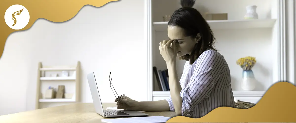 Woman experiencing eye strain while working on a laptop, indicating possible digital eye fatigue or vision issues related to prolonged screen use