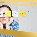 Woman wearing paper cutouts of eyes over her glasses, symbolising blurred or distorted vision linked to eye conditions like keratoconus