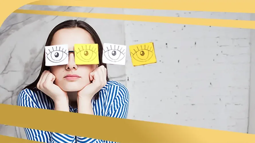 Woman wearing paper cutouts of eyes over her glasses, symbolising blurred or distorted vision linked to eye conditions like keratoconus