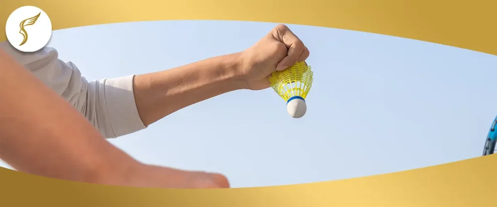 Hand holding a badminton shuttlecock against the sky, illustrating hand-eye coordination and visual tracking skills.