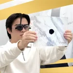 Patient undergoing eye exam at Shinagawa Lasik & Aesthetics using occluder glasses and pinhole test chart to assess visual acuity and refractive errors.
