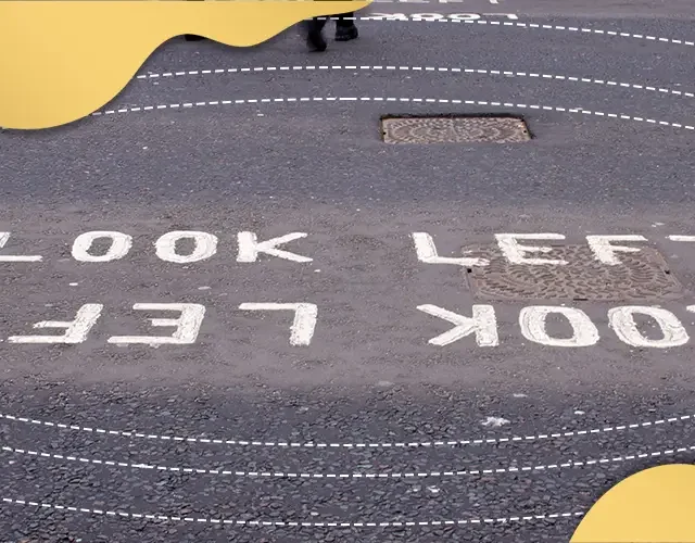 Road marking reading ‘Look Left’ on pedestrian crossing, illustrating visual awareness, directional perception, and road safety cues.