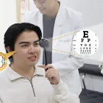Patient performing visual acuity test using occluder and Snellen eye chart during comprehensive eye exam at a LASIK and vision care clinic.