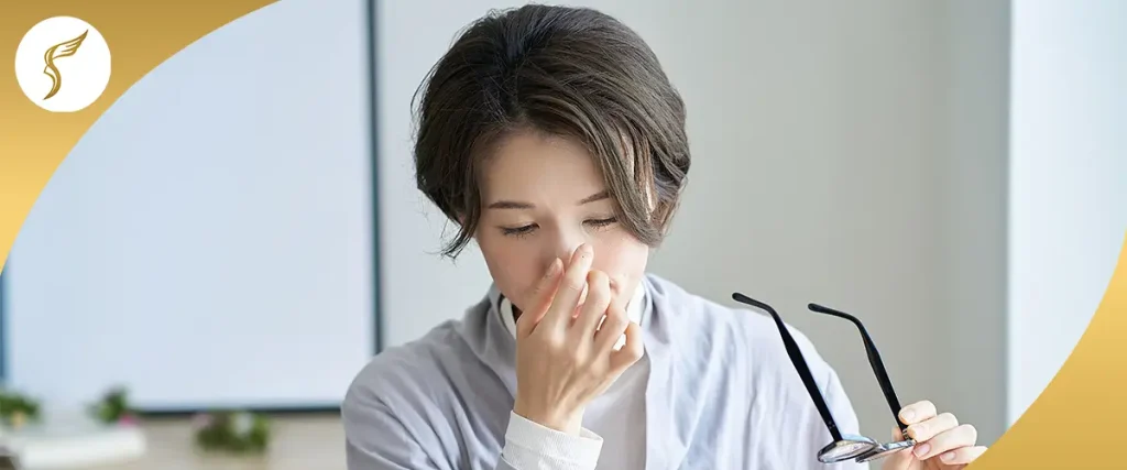 Woman rubbing her eyes while holding eyeglasses, showing eye strain, visual fatigue, or blurred vision